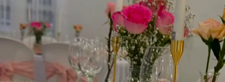 Centros de mesa con rosas fucsia y durazno, velas y copas