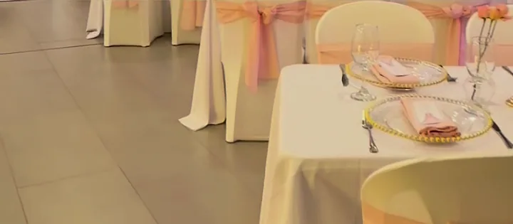 Mesas con mantel blanco y sillas vestidas con lazos rosados